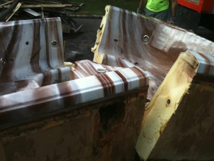 Broken pieces of an old hot tub being removed by a worker